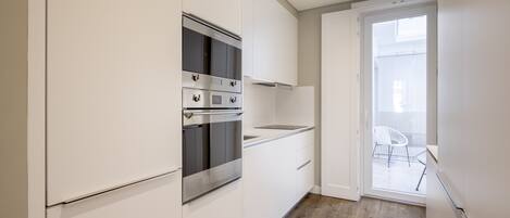 Una cocina moderna con armarios blancos, electrodomésticos de acero inoxidable y piso de madera.