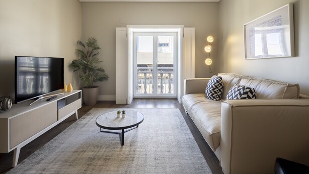 Ein modernes Wohnzimmer mit Sofa, Couchtisch, Fernseher und einer Topfpflanze.