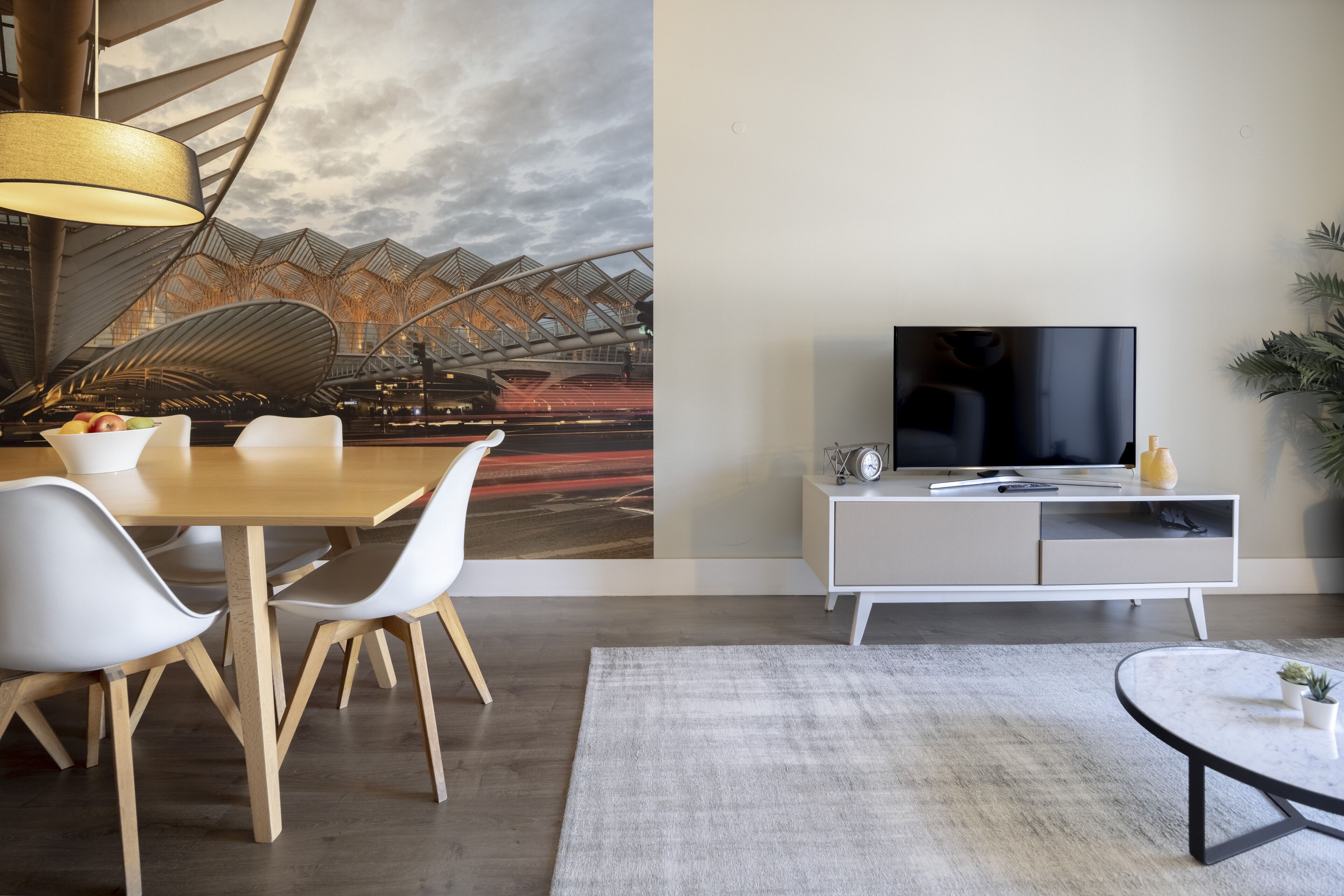 Una sala de estar moderna con comedor, televisor de pantalla plana y un gran mural abstracto en la pared.