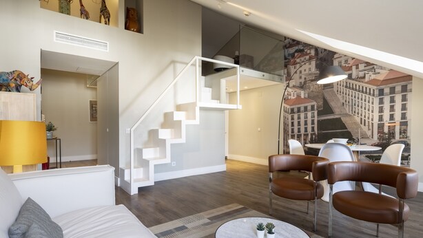 Ein modernes Wohnzimmer mit Treppe, Essbereich und Stadtbild-Wandgemälde.