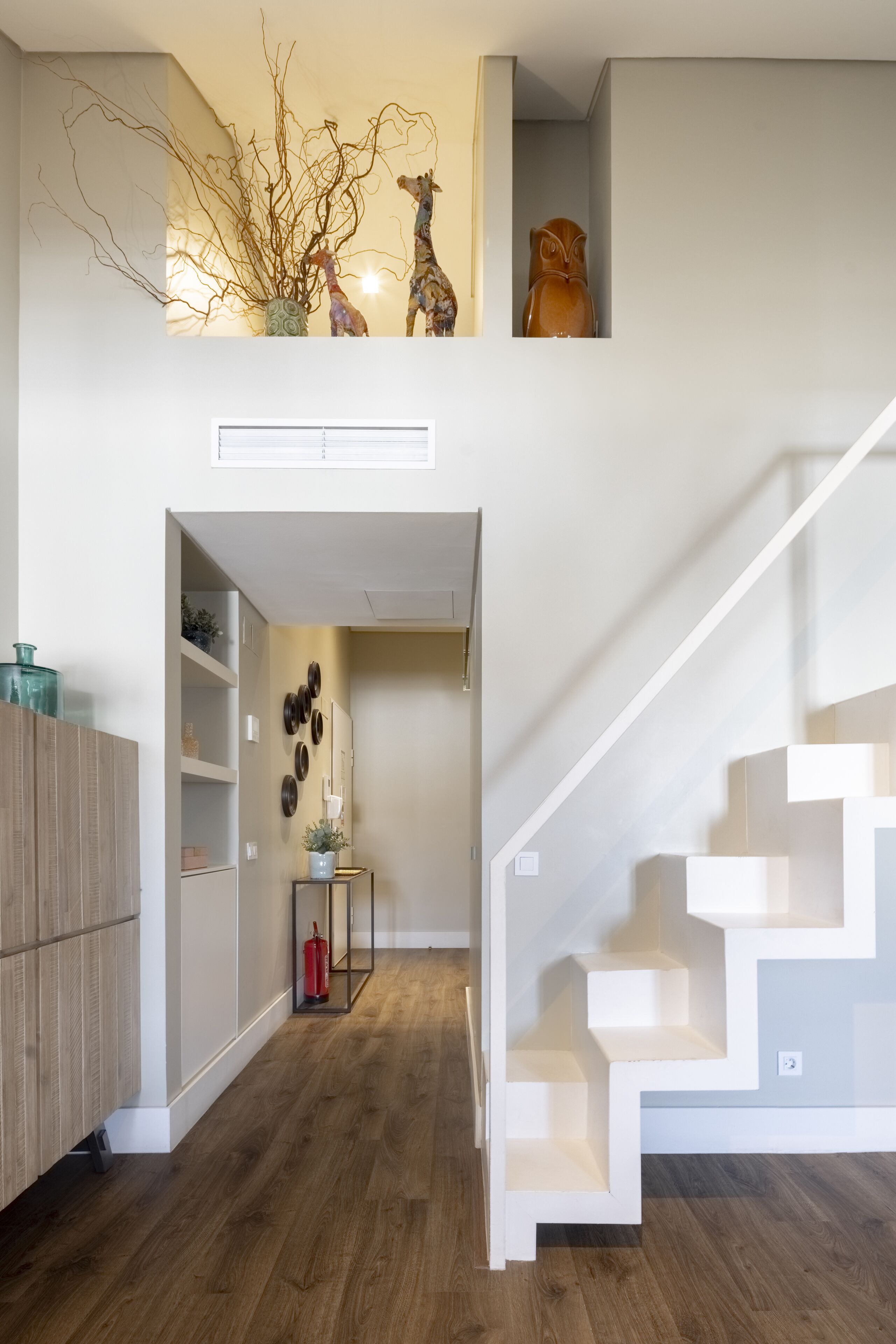A modern interior with a staircase, wooden flooring, and a decorative wall piece.