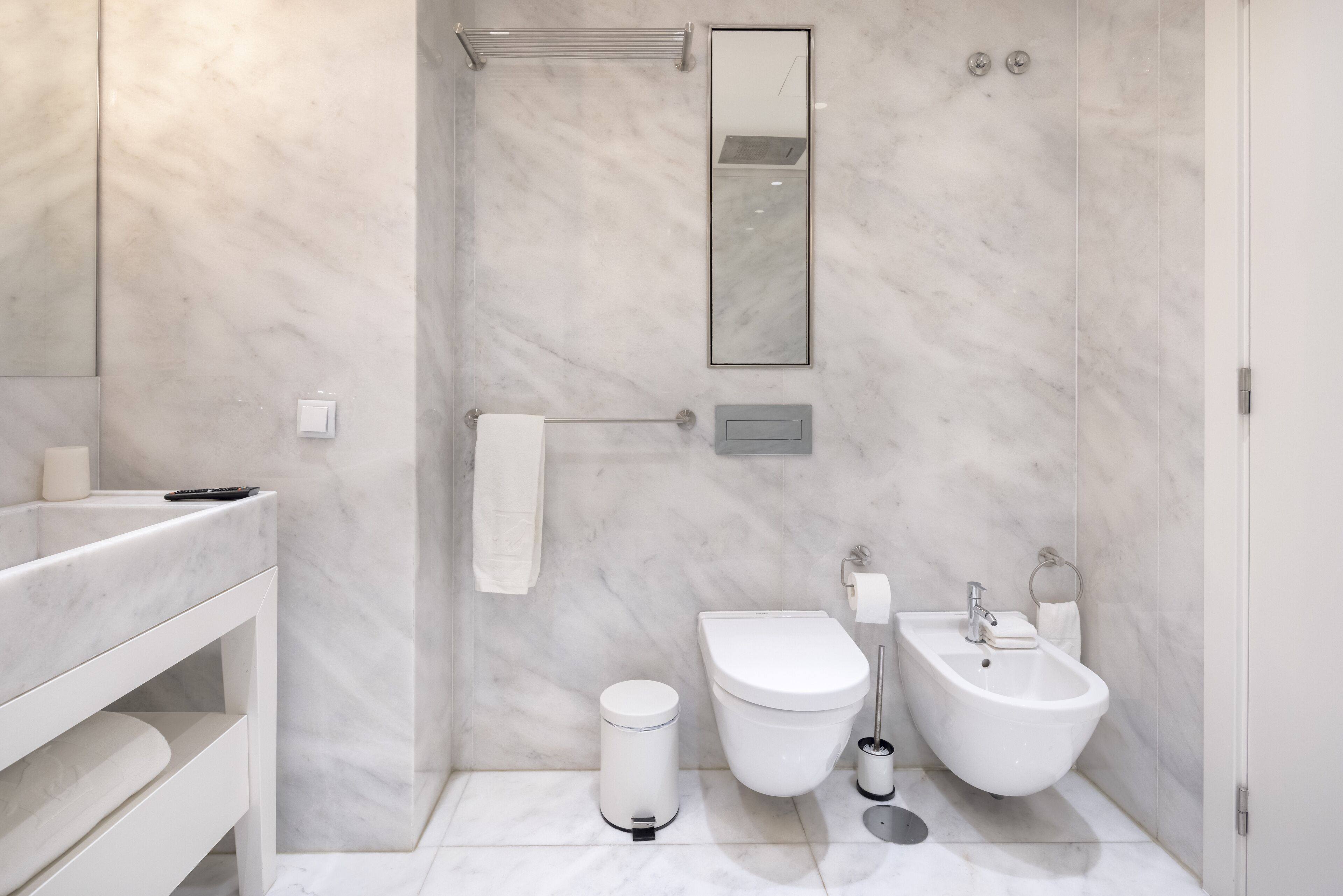 Ein modernes Badezimmer mit Toilette, Bidet und Waschbecken, alles in Weiß.