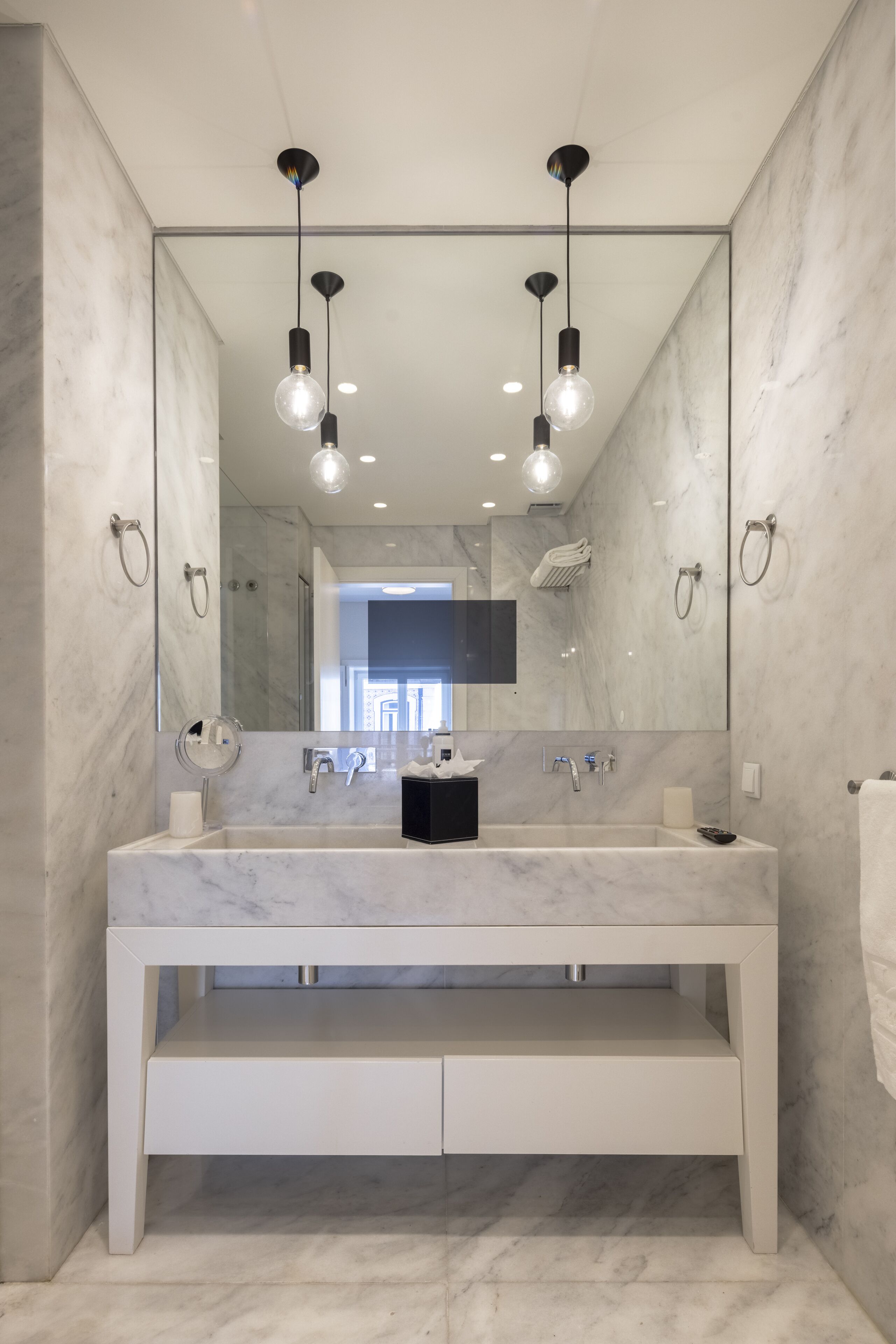 Un baño moderno con tocador de mármol, doble lavabo y un espejo grande.
