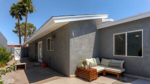 A modern house with a grey exterior, a patio area with a white bench, a wooden table, and a beige sofa with colorful pillows. - PX032 4 Bedroom Holiday home By Senstay (Scottsdale)