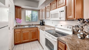 A kitchen with wooden cabinets, a microwave, a stove, and a sink. - PX033 1 Bedroom Apartment By Senstay (Phoenix)