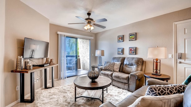 A living room with a leather sofa, a round coffee table, a TV on a wooden stand, and a ceiling fan. - PX033 1 Bedroom Apartment By Senstay (Phoenix)