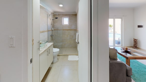 A modern bathroom with a glass shower enclosure, a toilet, and a sink with a glass bowl.