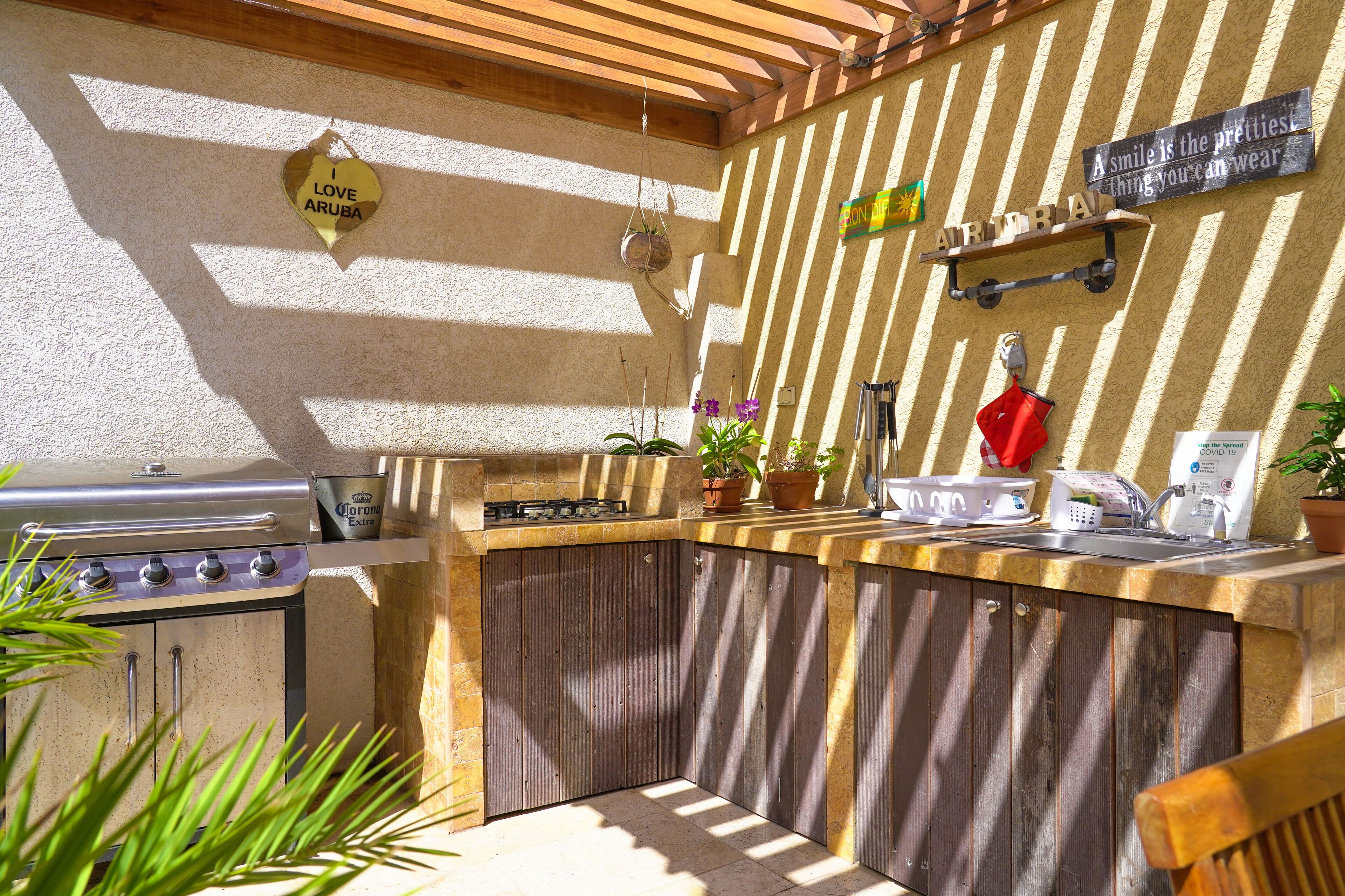 An outdoor kitchen with a gas stove, a sink, and a wooden countertop.