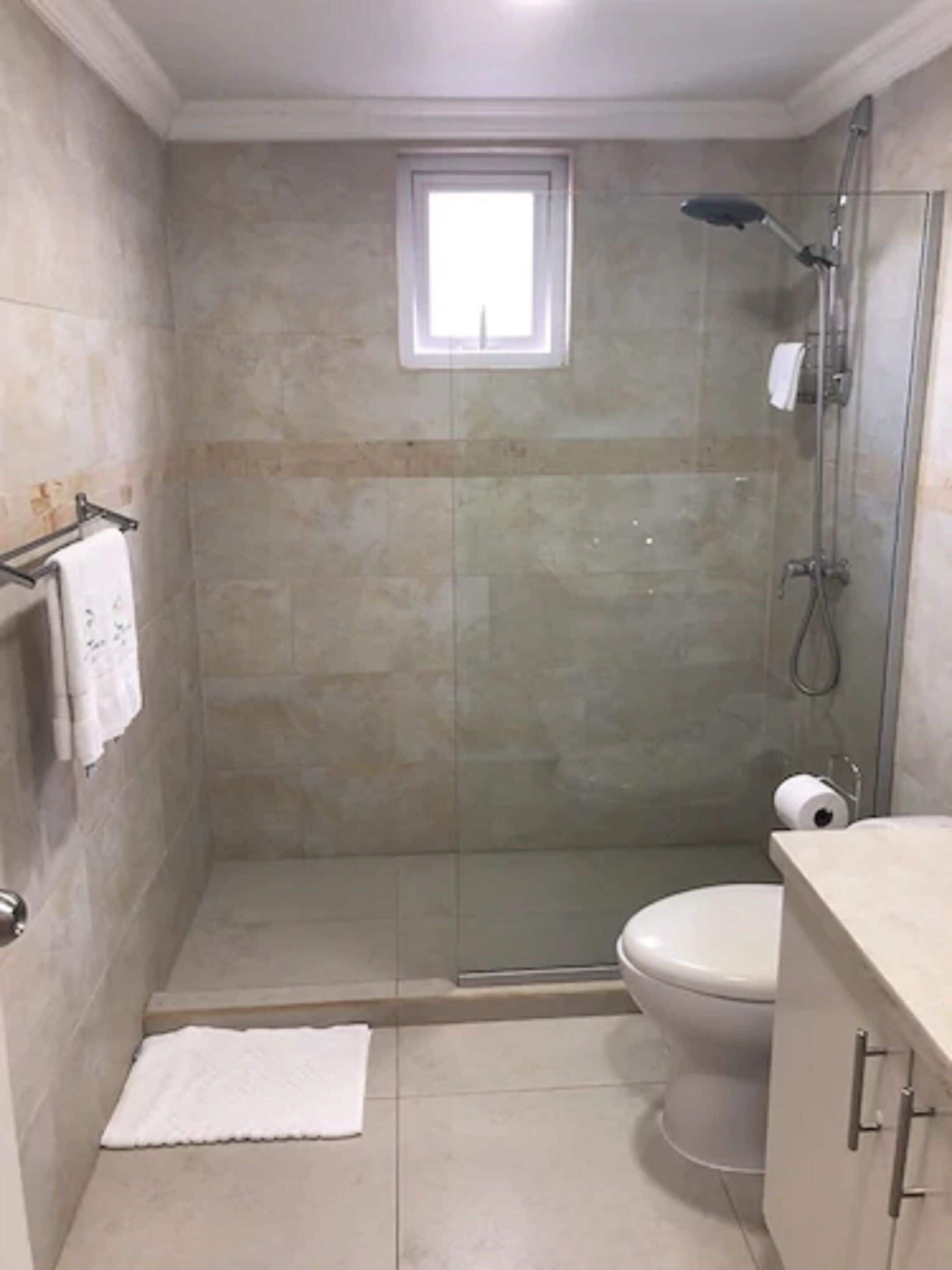 Ein Badezimmer mit einer Duschkabine, einer Toilette und einem kleinen Fenster.