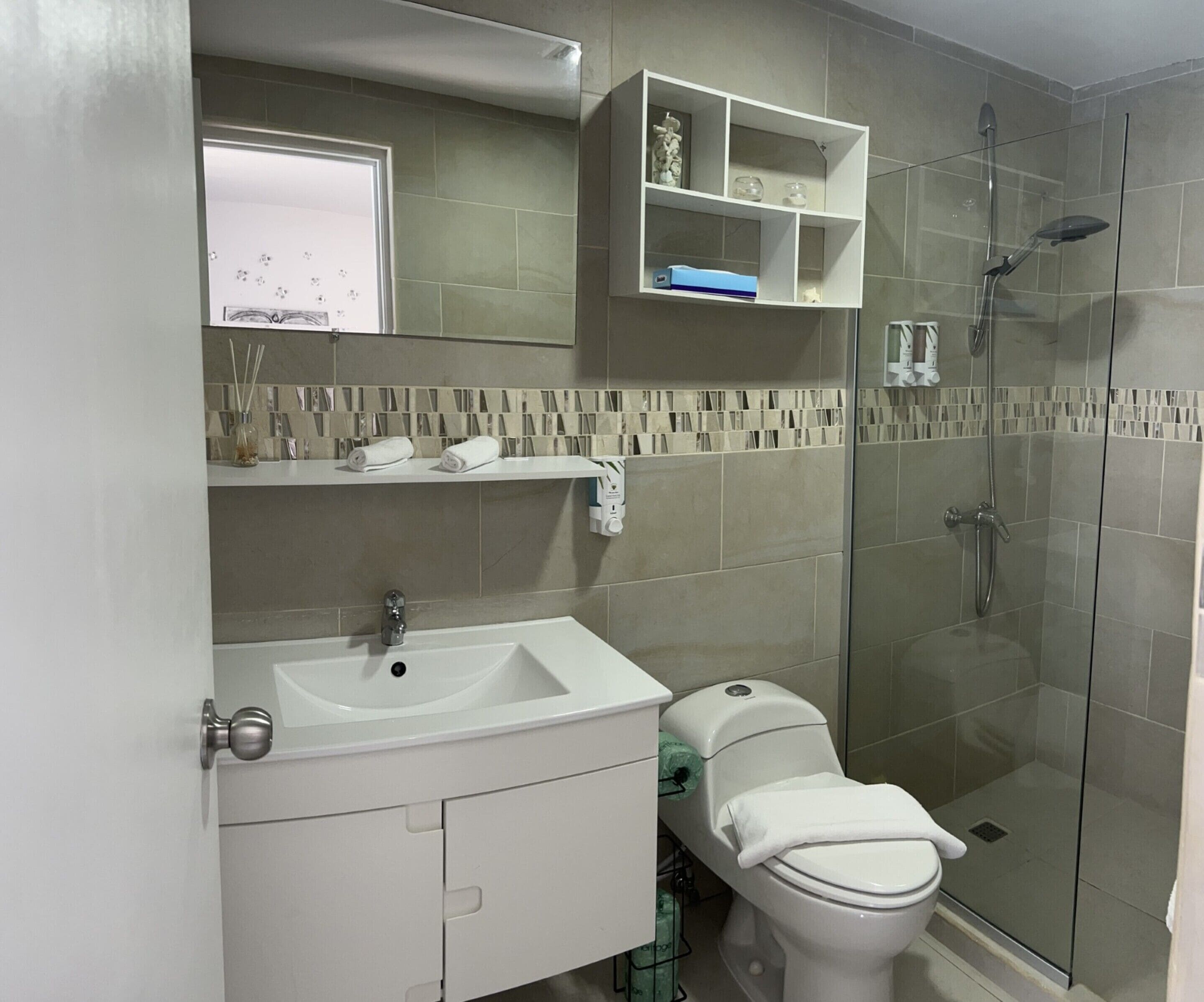 A modern bathroom with a white sink, toilet, and glass shower enclosure.