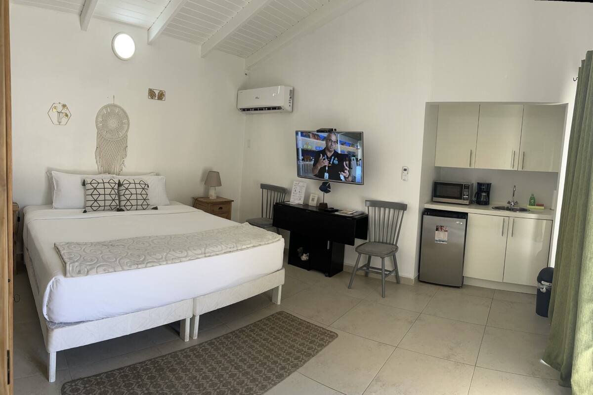 Un dormitorio con cama, mesita de noche, lámpara y televisor montado en la pared.