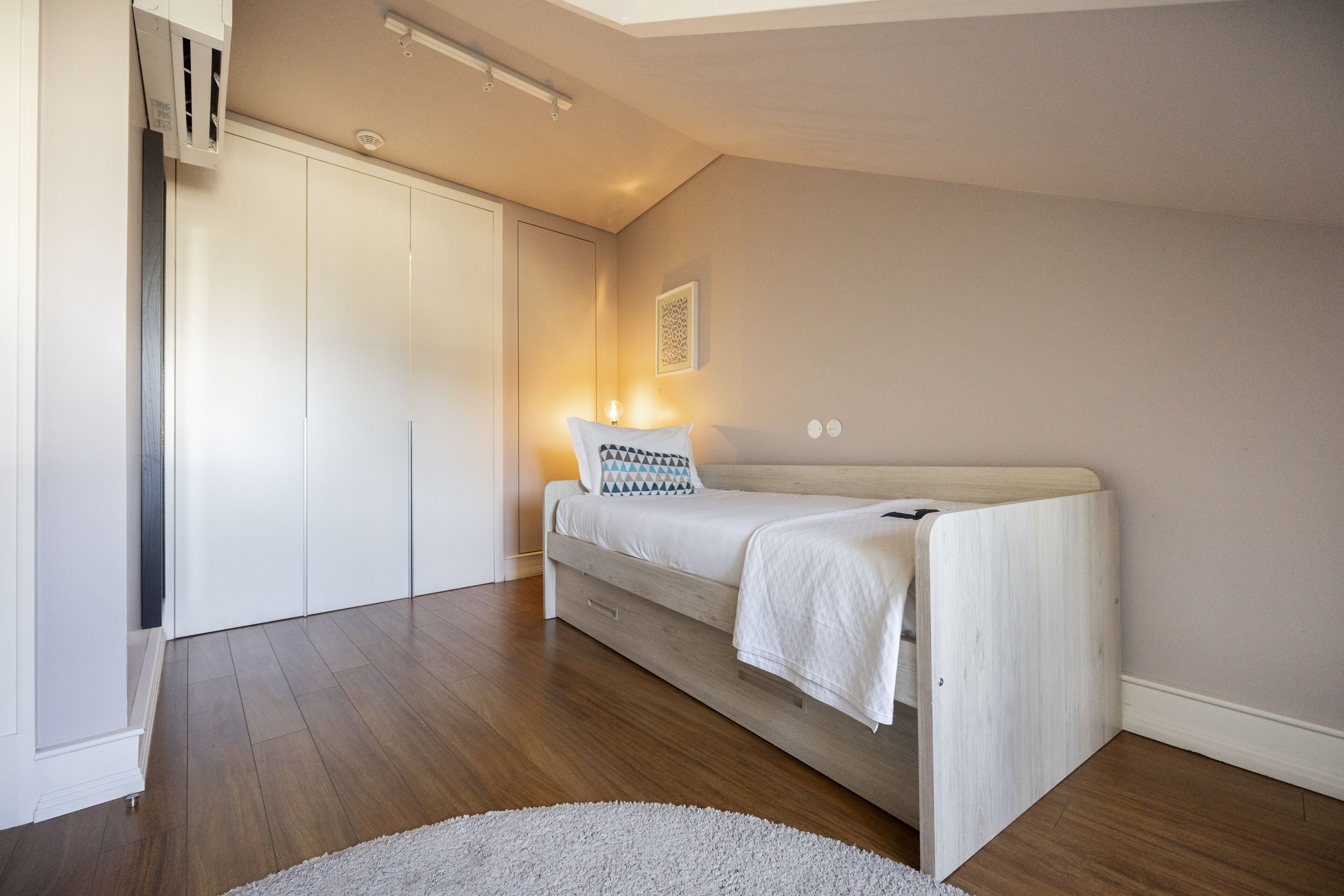 Une chambre à coucher avec un lit, une armoire blanche et un petit tapis.