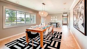 A dining area with a long wooden table, black and white patterned rug, and a chandelier. - PX037 3 Bedroom Apartment By Senstay (Phoenix)