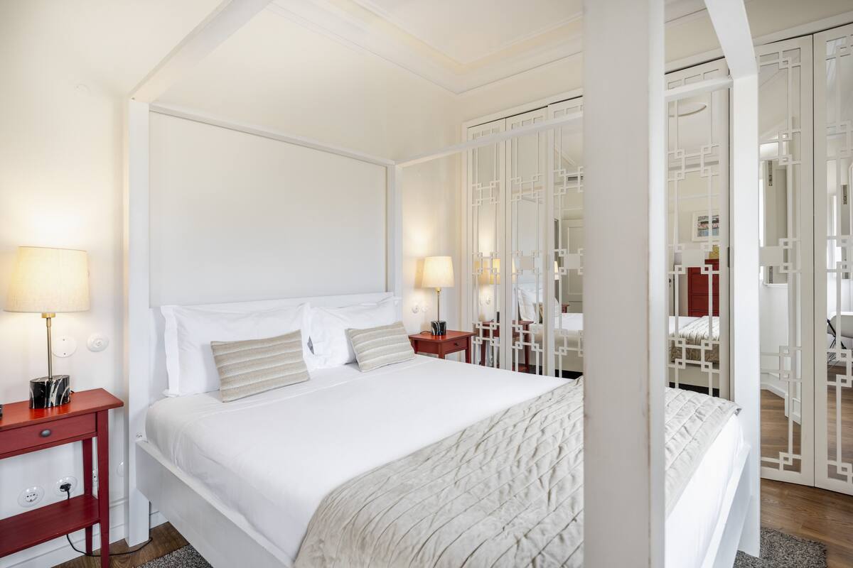 Une chambre d’hôtel avec un grand lit, des tables de chevet, une armoire et un miroir.