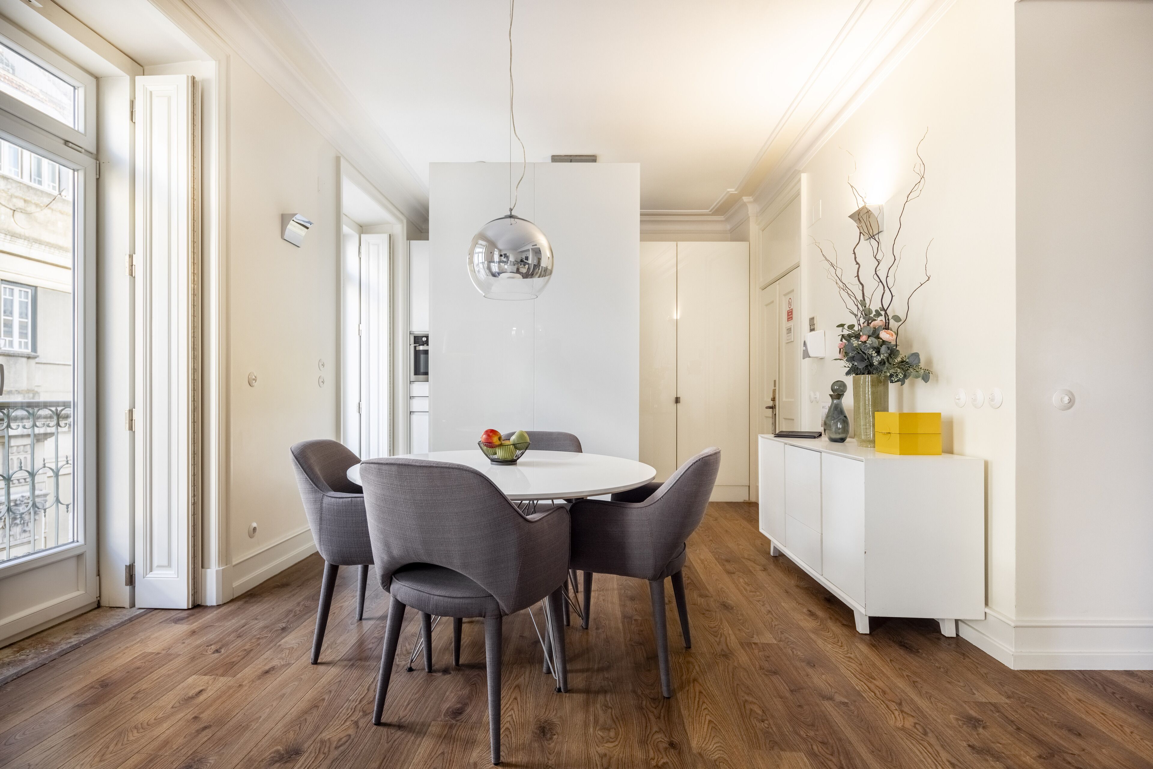Un coin repas comprenant une table ronde, quatre chaises et un luminaire suspendu.