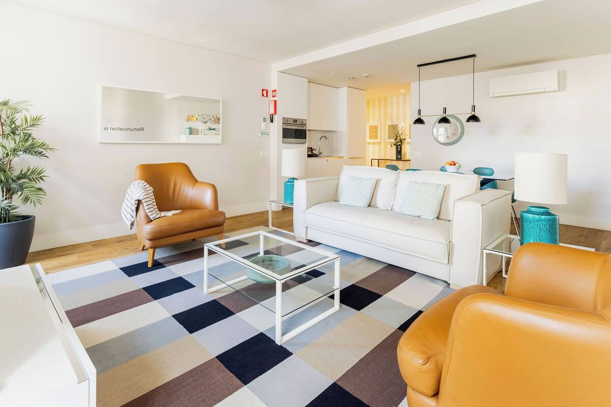 Un salon moderne avec un canapé, un fauteuil, une table basse et une plante en pot.
