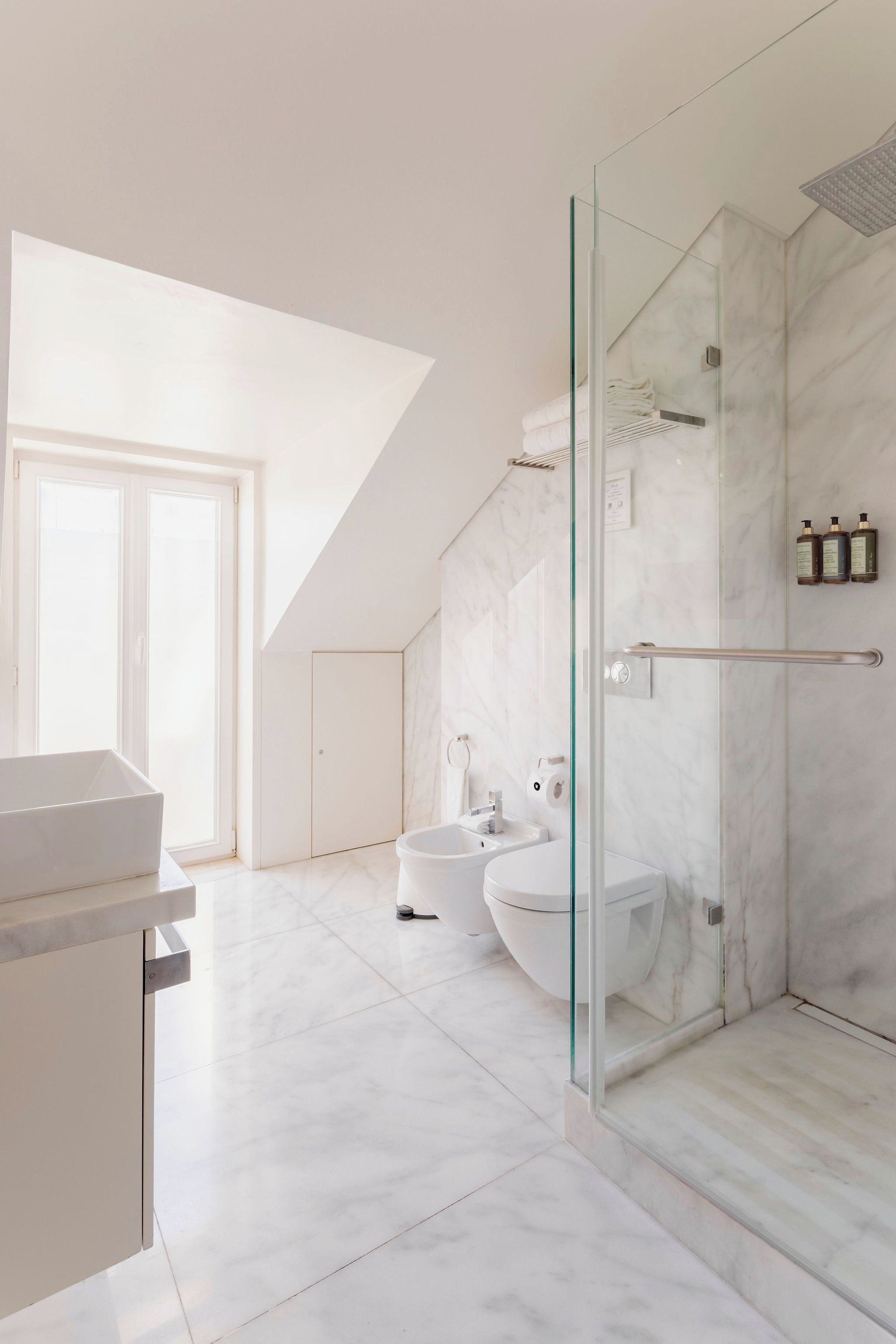 A modern bathroom with a glass-enclosed shower, a freestanding bathtub, and a toilet.