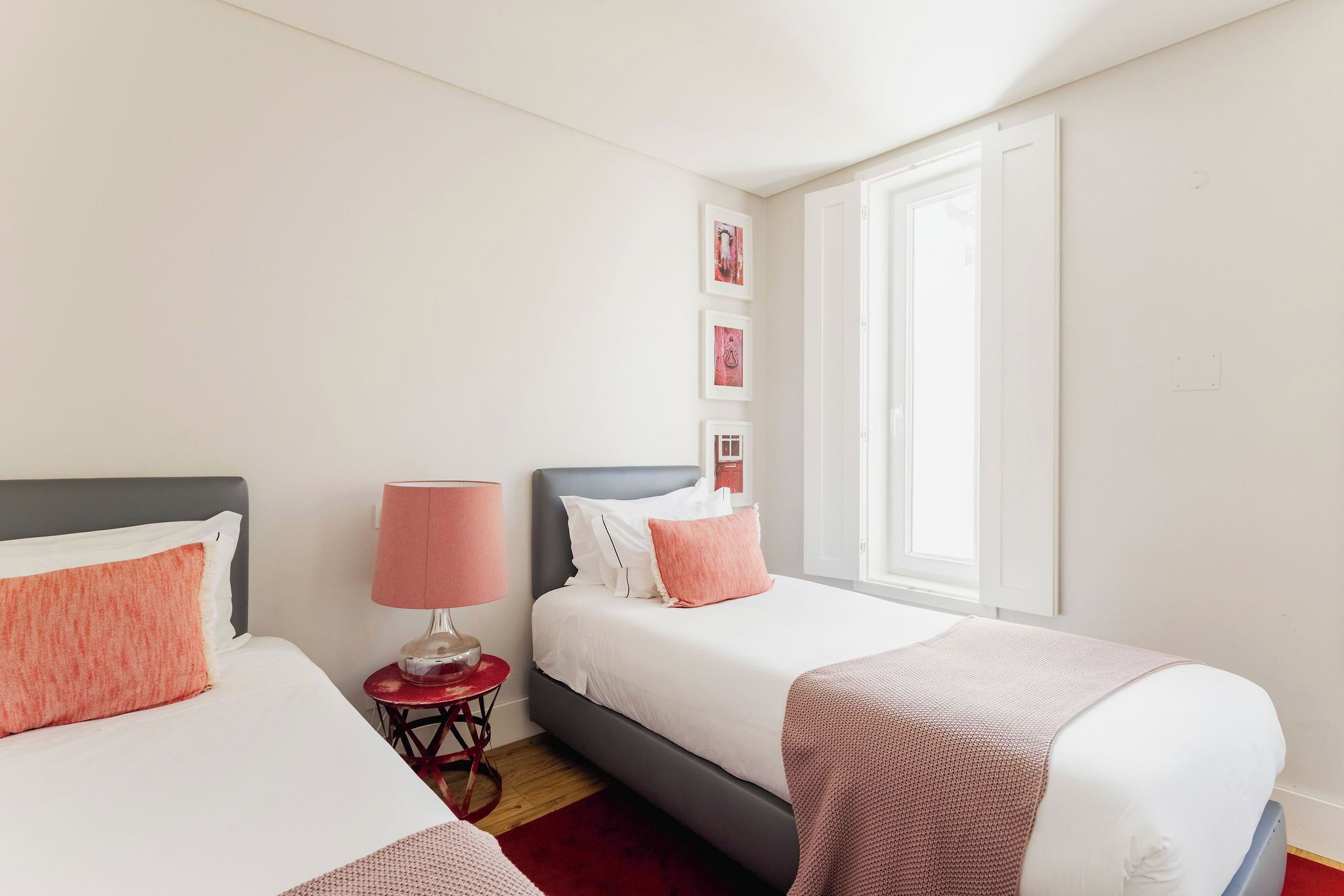 A hotel room with two beds, a red lamp, and a window.