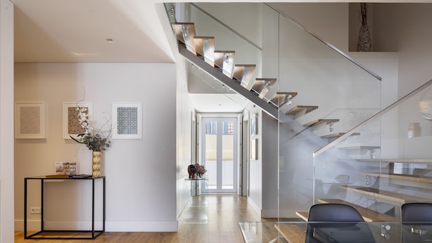 A modern interior with a staircase, a glass table, and framed artwork on the walls. - Chiado Square - Lisbon Best Apartments (Lisbon)