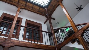 A wooden staircase with a glass ceiling, brick walls, and a chandelier. - Hotel Casa Ecuatreasures Centro Histórico (Quito)