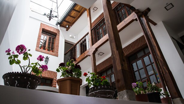 A multi-level interior with wooden beams, potted plants, and a skylight. - Hotel Casa Ecuatreasures Centro Histórico (Quito)