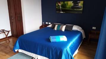 Un dormitorio con una cama, un cuadro, una puerta de madera y una mesita.