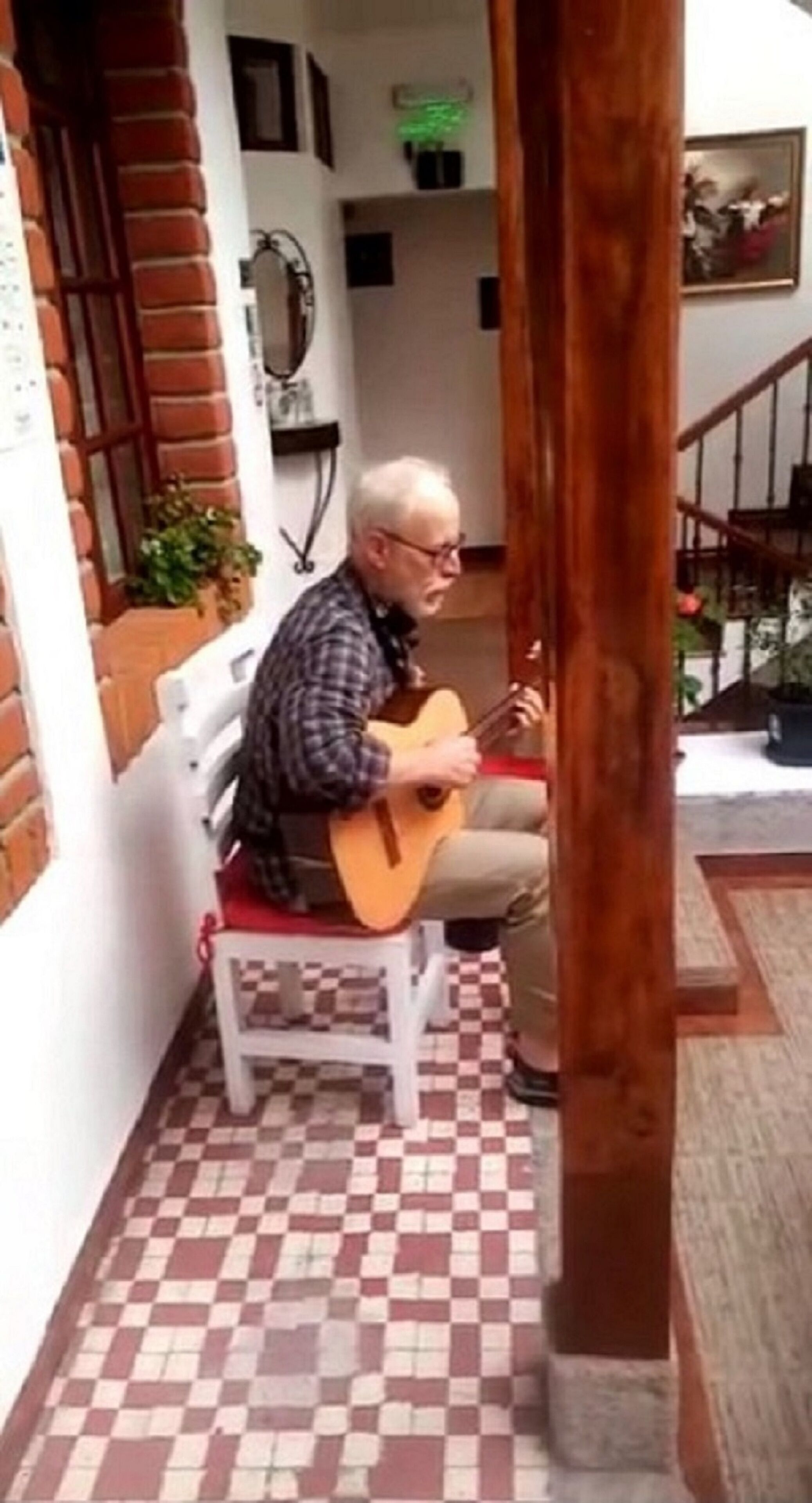 Una persona sentada en una silla blanca tocando una guitarra.