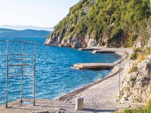 Une zone côtière caractérisée par une côte rocheuse, une structure métallique et une mer d’un bleu limpide.