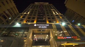 Un hotel con un cartel llamativo de Best Western PLUS y un Haji Ali Juice Center.