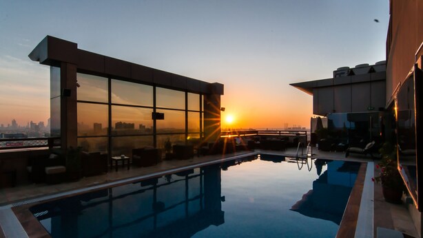 Una piscina en la azotea con vistas al horizonte urbano al atardecer.