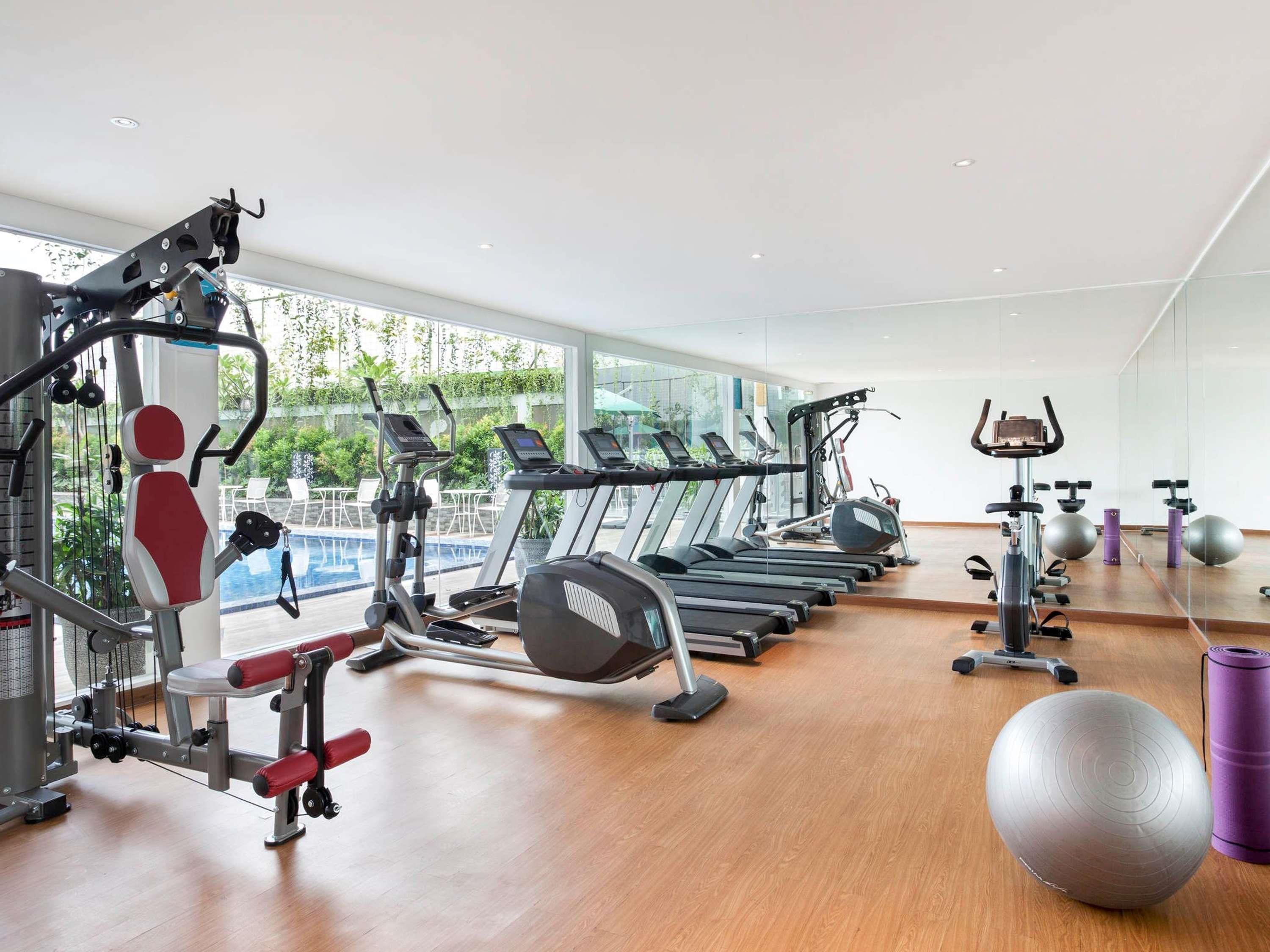A modern gym with various cardio machines, free weights, and exercise balls.