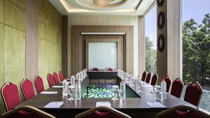 Uma sala de conferência com uma mesa comprida, cadeiras, garrafas de água e um amplo janelão.