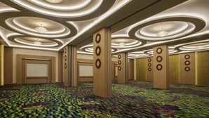 Um hall de hotel espaçoso com carpete xadrez, painéis de madeira e luminárias de teto circulares.