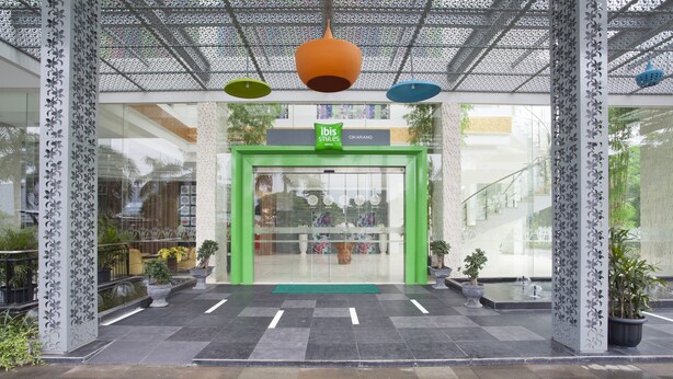 A modern entrance with a green door, potted plants, and a patterned column. - Ibis Styles Cikarang (Cikarang)