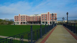 A Courtyard hotel with a red and white facade, a green lawn, and a paved walkway with black railings.