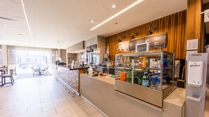A modern hotel lobby with a seating area, a refreshment bar, and a view of the city. - Courtyard by Marriott Rome (Rome)
