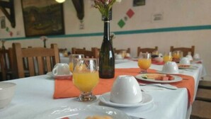 A breakfast setting with fruit, juice, and a white tablecloth. - Hotel San Luis (San Cristóbal de las Casas)