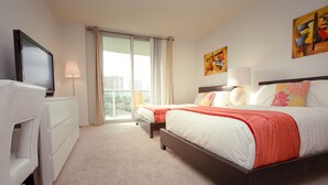 A hotel room with a large bed, a TV, a desk, and a balcony with a view of the city. - Sunny Isles Suites (Sunny Isles Beach)