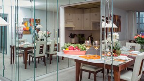A modern dining area with a glass partition, wooden furniture, and a kitchen in the background. - Sunny Isles Suites (Sunny Isles Beach)
