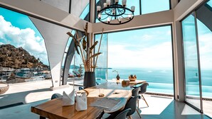A modern dining area with a wooden table, chairs, and a view of the ocean. - Sky Dream Villa (Koh Samui)