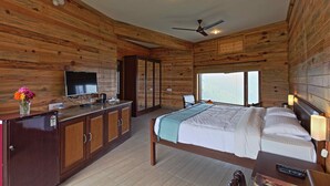 Ein Schlafzimmer mit Holzwandverkleidung, einem Bett, Nachttischen, einem Fernseher und einem Fenster.
