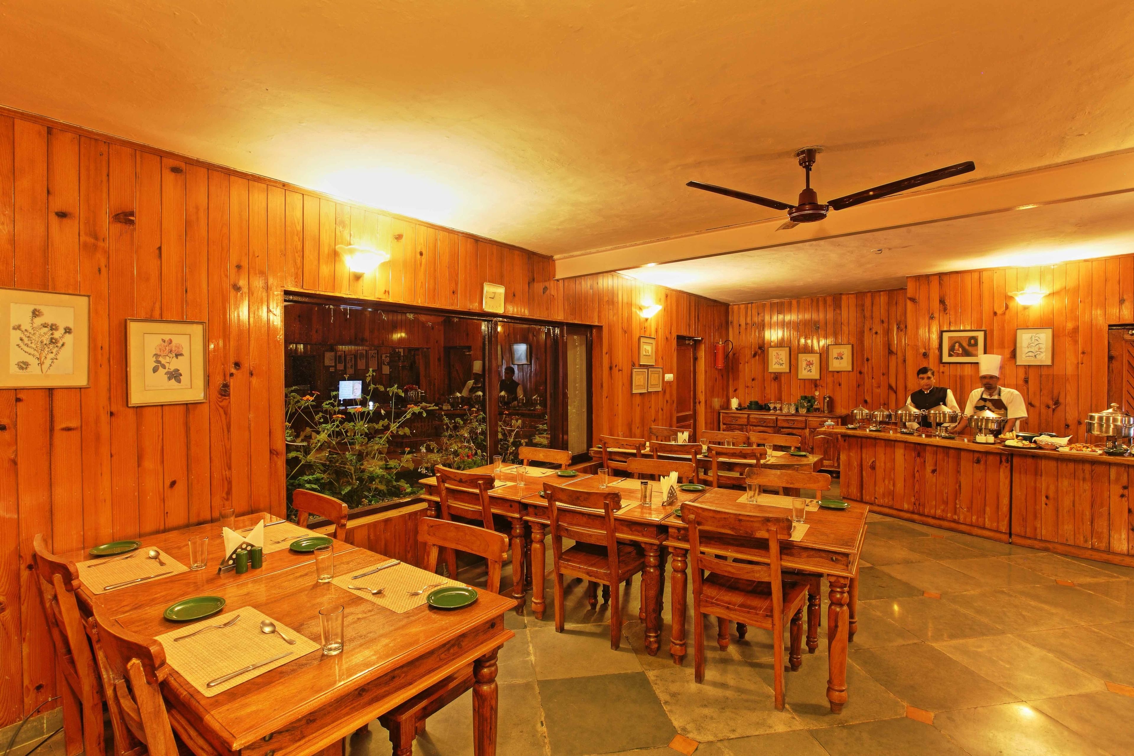 A restaurant with wooden walls and a bar area. Tables are set with green placemats and cutlery.