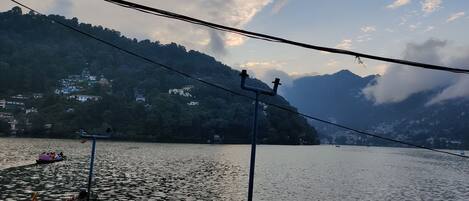 A lake with a boat docked on the shore, surrounded by hills and houses.
