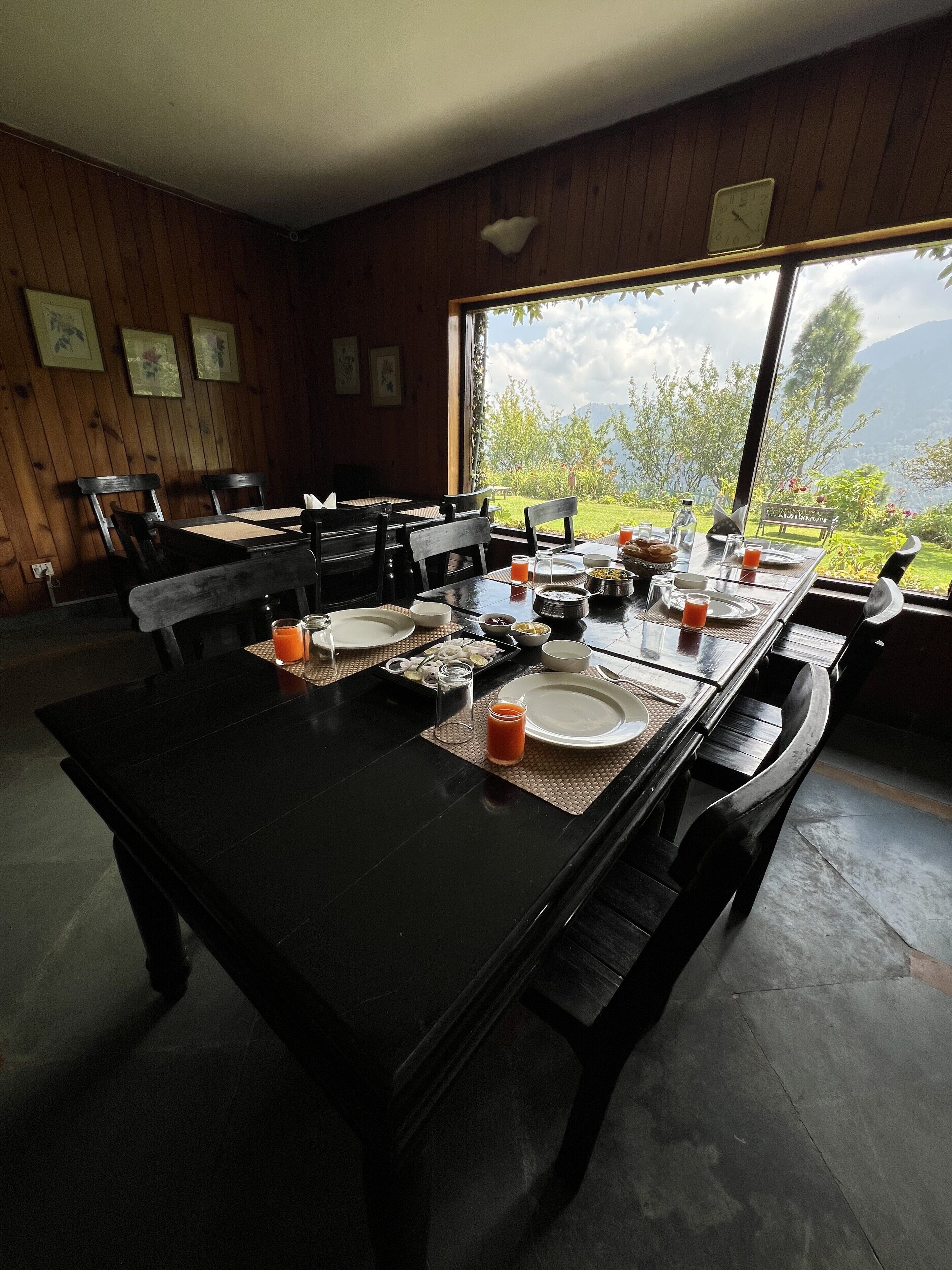 Un coin repas avec une table mise pour le petit-déjeuner, comprenant des assiettes, des verres et une carafe de jus de fruits.
