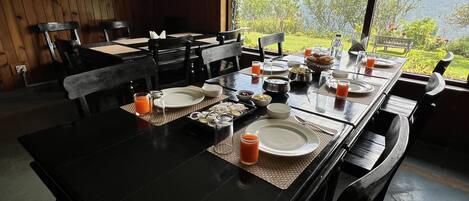 Un coin repas avec une table mise pour le petit-déjeuner, comprenant des assiettes, des verres et une carafe de jus de fruits.