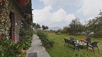 Un jardín con un sendero que lleva a una mesa y sillas, rodeado de abundante follaje y flores.