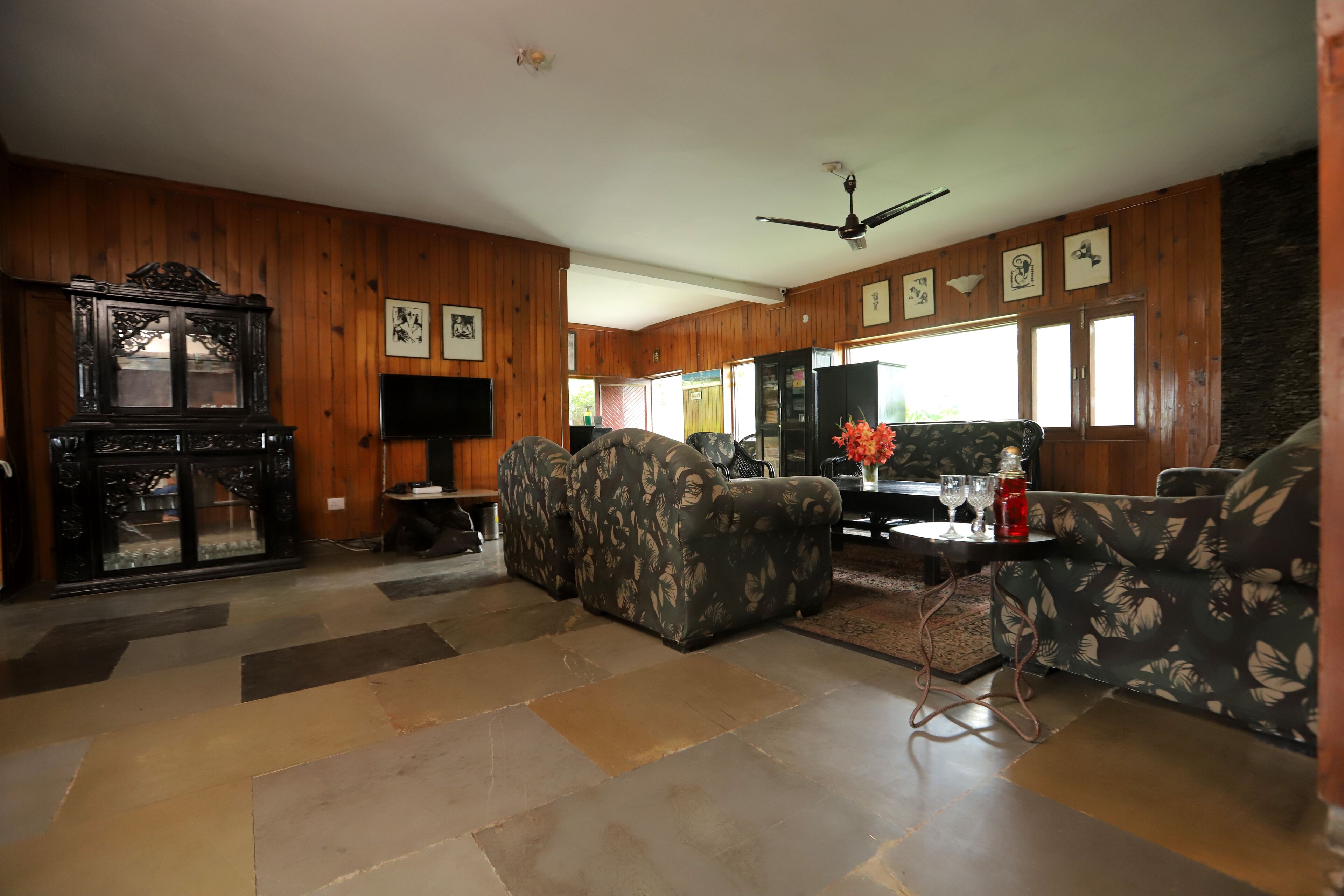A spacious living room with a large sofa, a television, and a wooden cabinet.