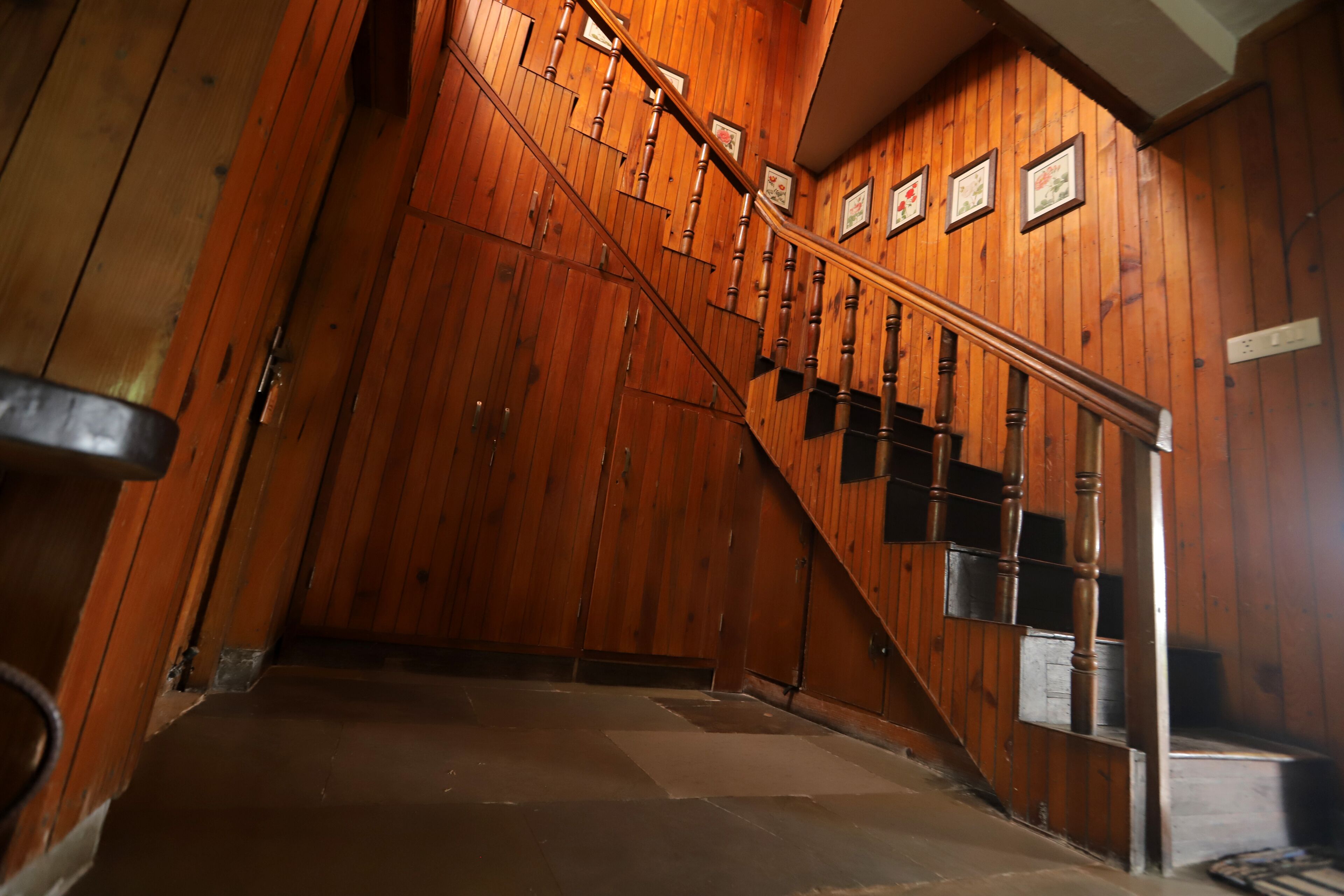 Una escalera de madera con barandilla que conduce a un rellano con una puerta.