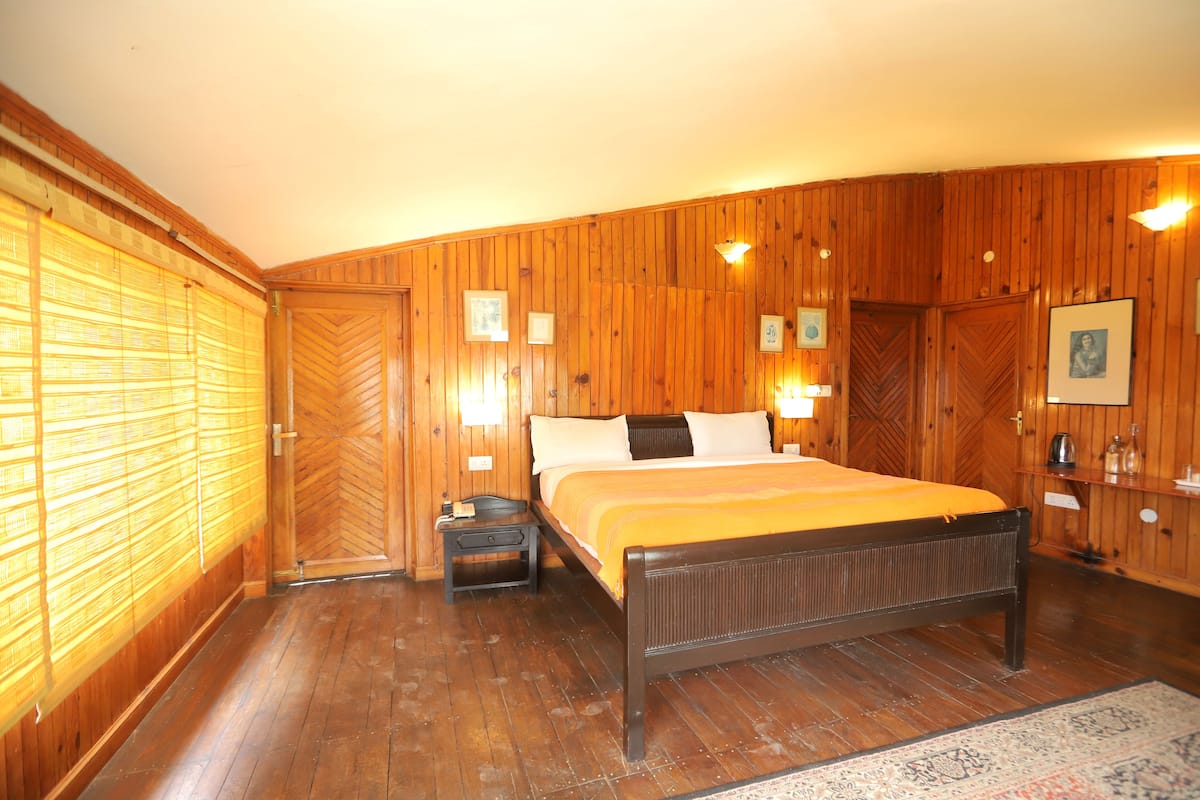 Une chambre à coucher aux murs lambrissés, avec un lit, des tables de chevet et une petite table de nuit.
