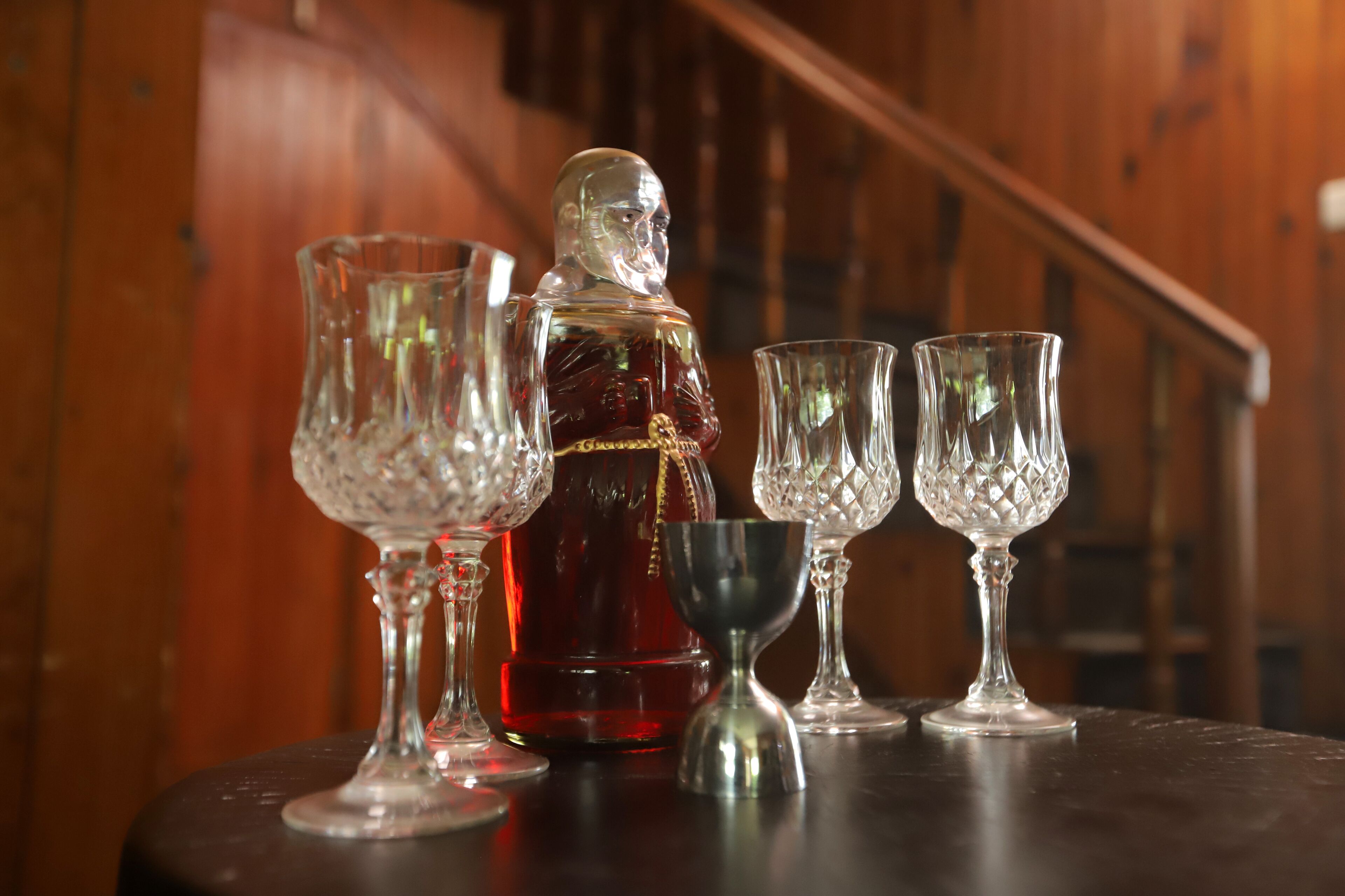 Une table avec une carafe et quatre verres, le tout placé sur un fond en bois.
